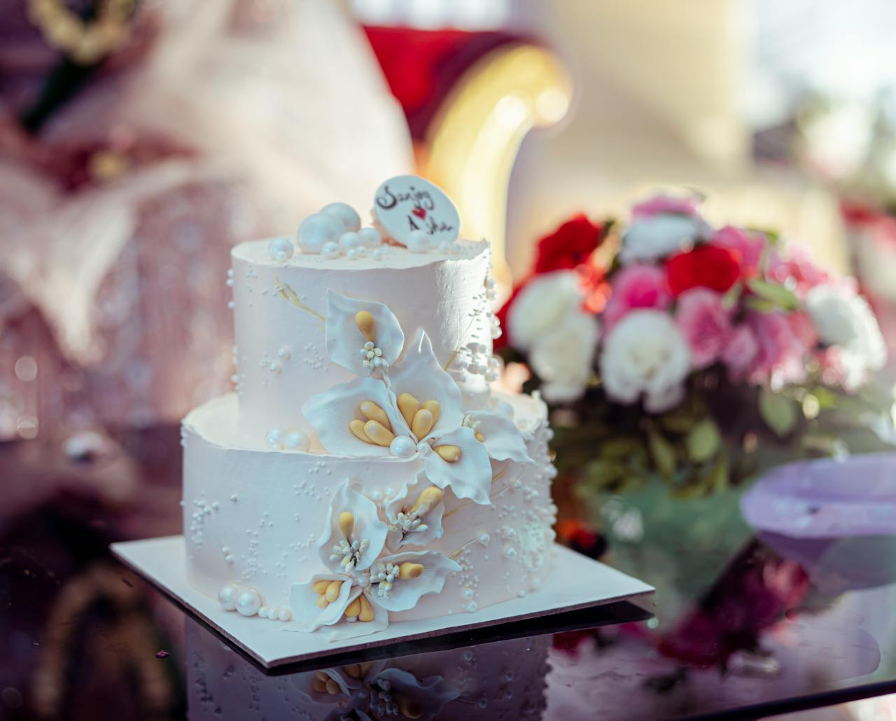 A beautifully decorated two-tier wedding cake featuring elegant floral motifs and intricate details.